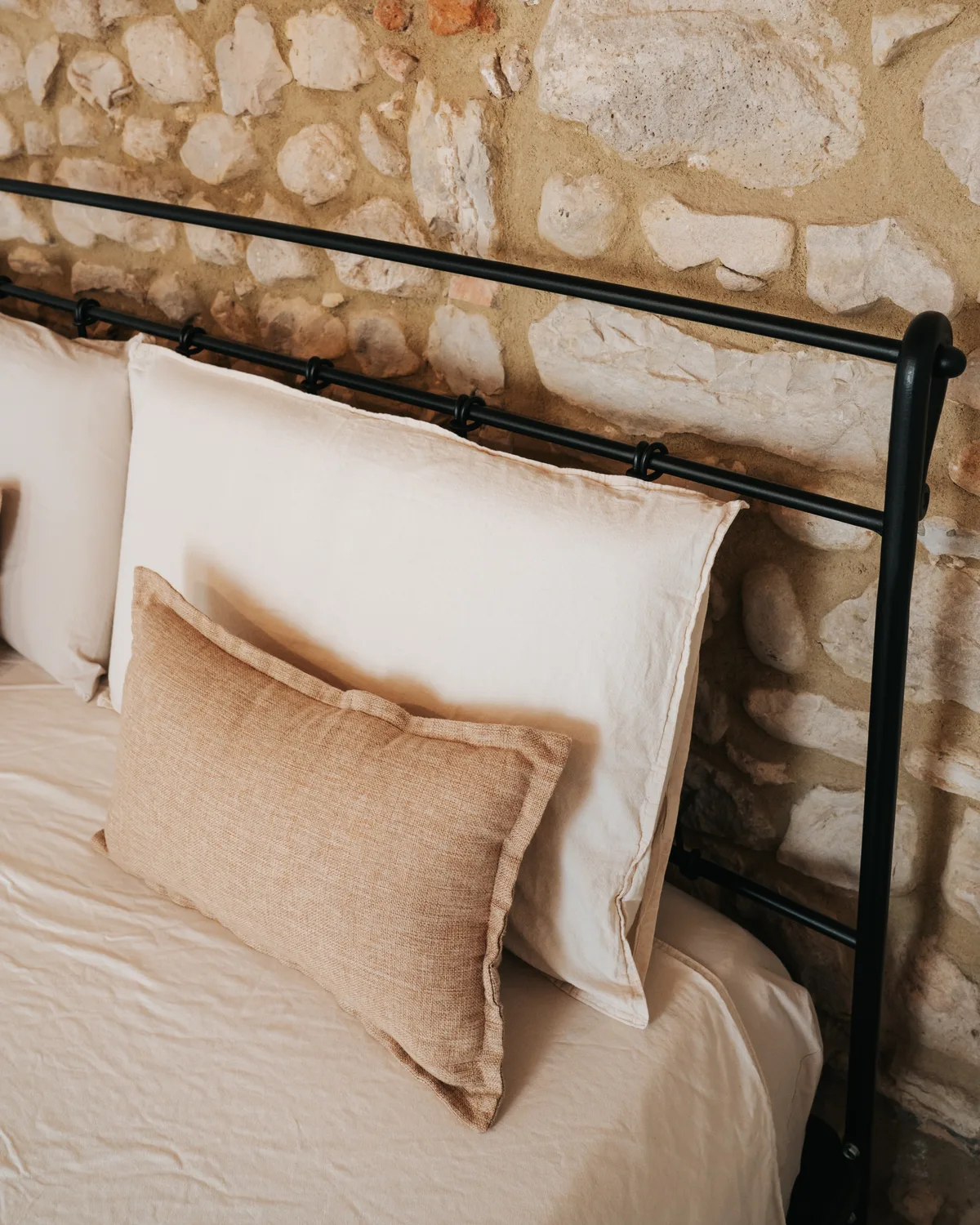 Soft pillows and natural linen against an exposed stone wall