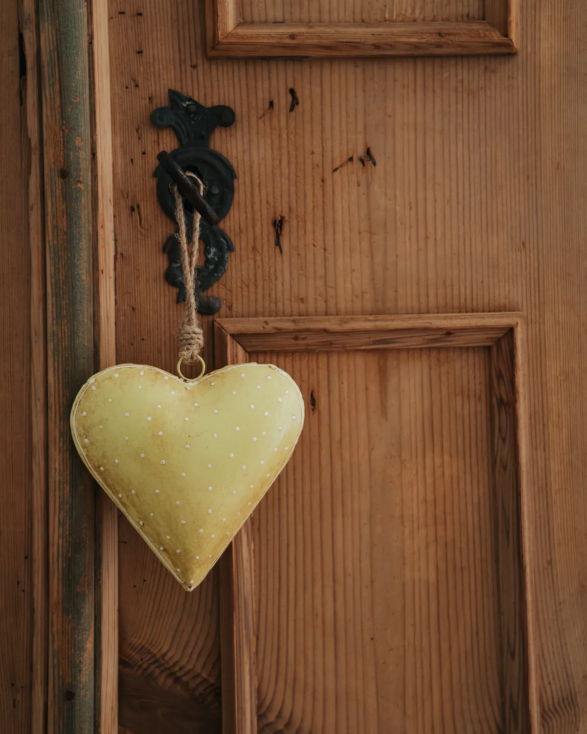 A small fabric heart hanging from an old wooden cupboard