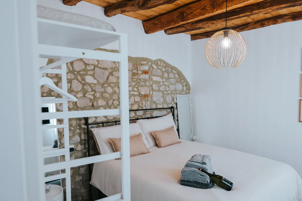 A welcoming bedroom with exposed stone, wooden beams and natural fabrics